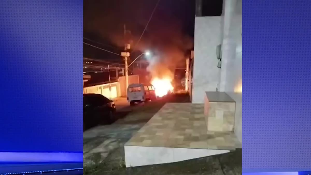 Carro em chamas estacionado em uma rua à noite