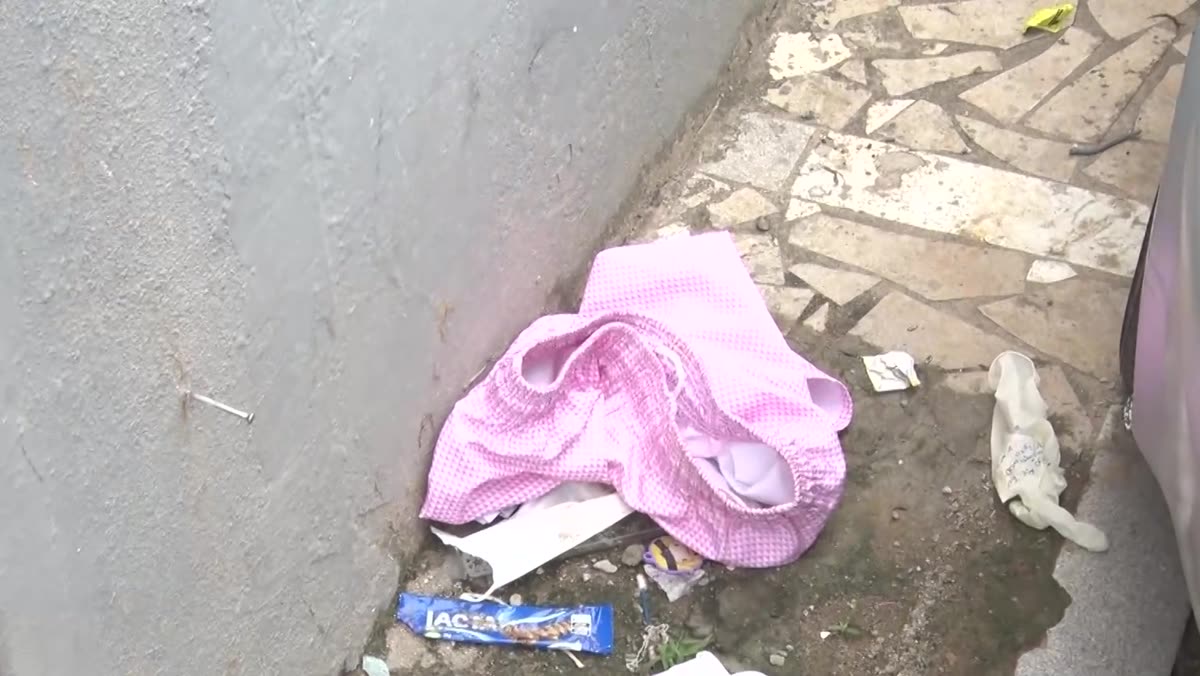Beco no bairro Perocão com objetos deixados no chão ao lado de um carro