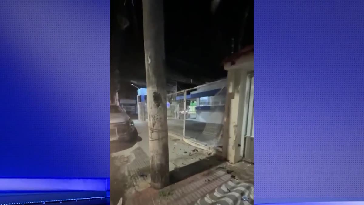 Portão de garagem com grade danificada ao lado de um poste