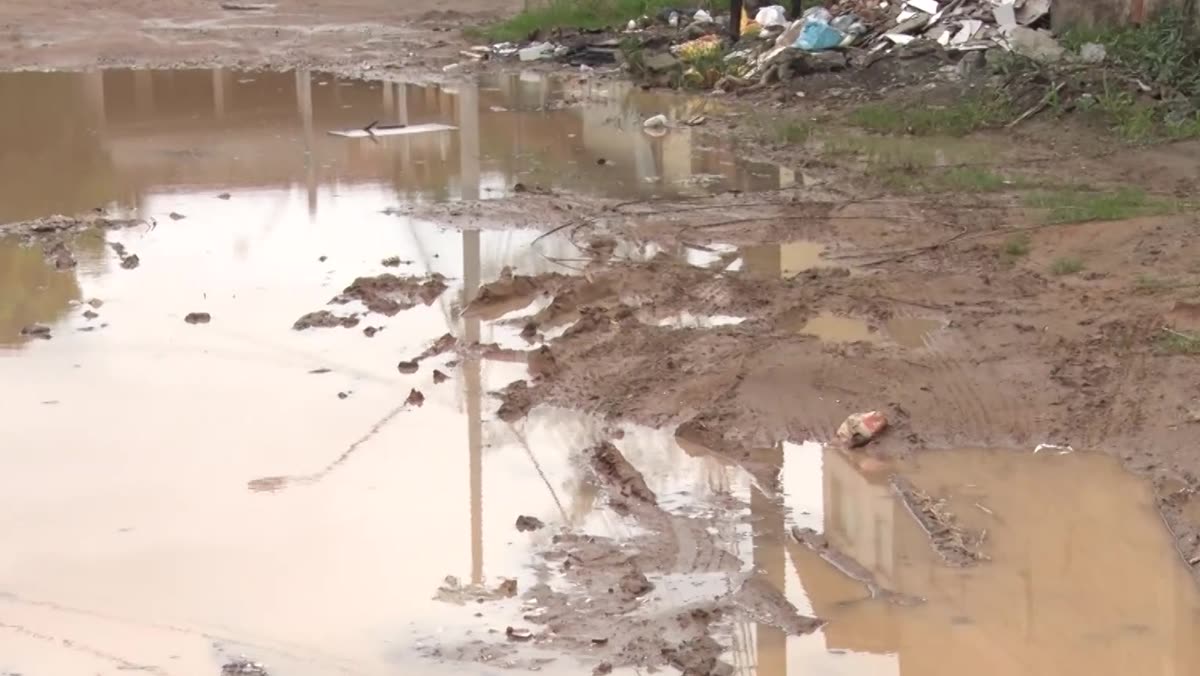 Trecho em aclive de rua sem pavimentação, com valas