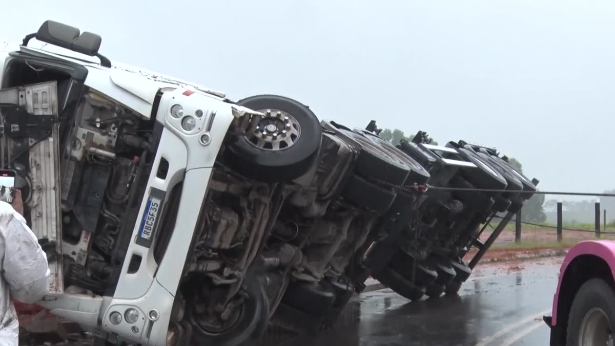 Caminhões rebocadores ao lado da carreta tombada na rodovia
