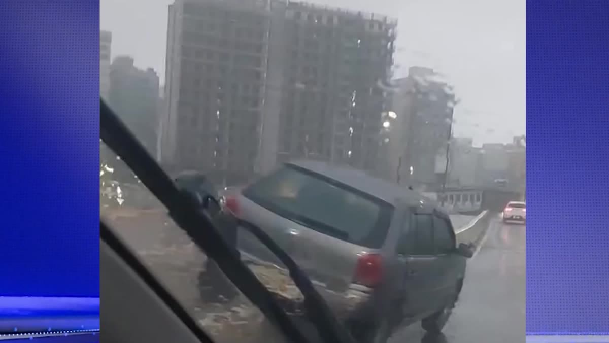 Carro prata parado sobre a ciclovia da ponte de Guarapari durante chuva